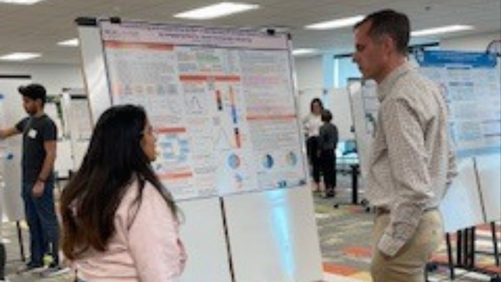 Poster presenter in front of poster speaking to onlooker