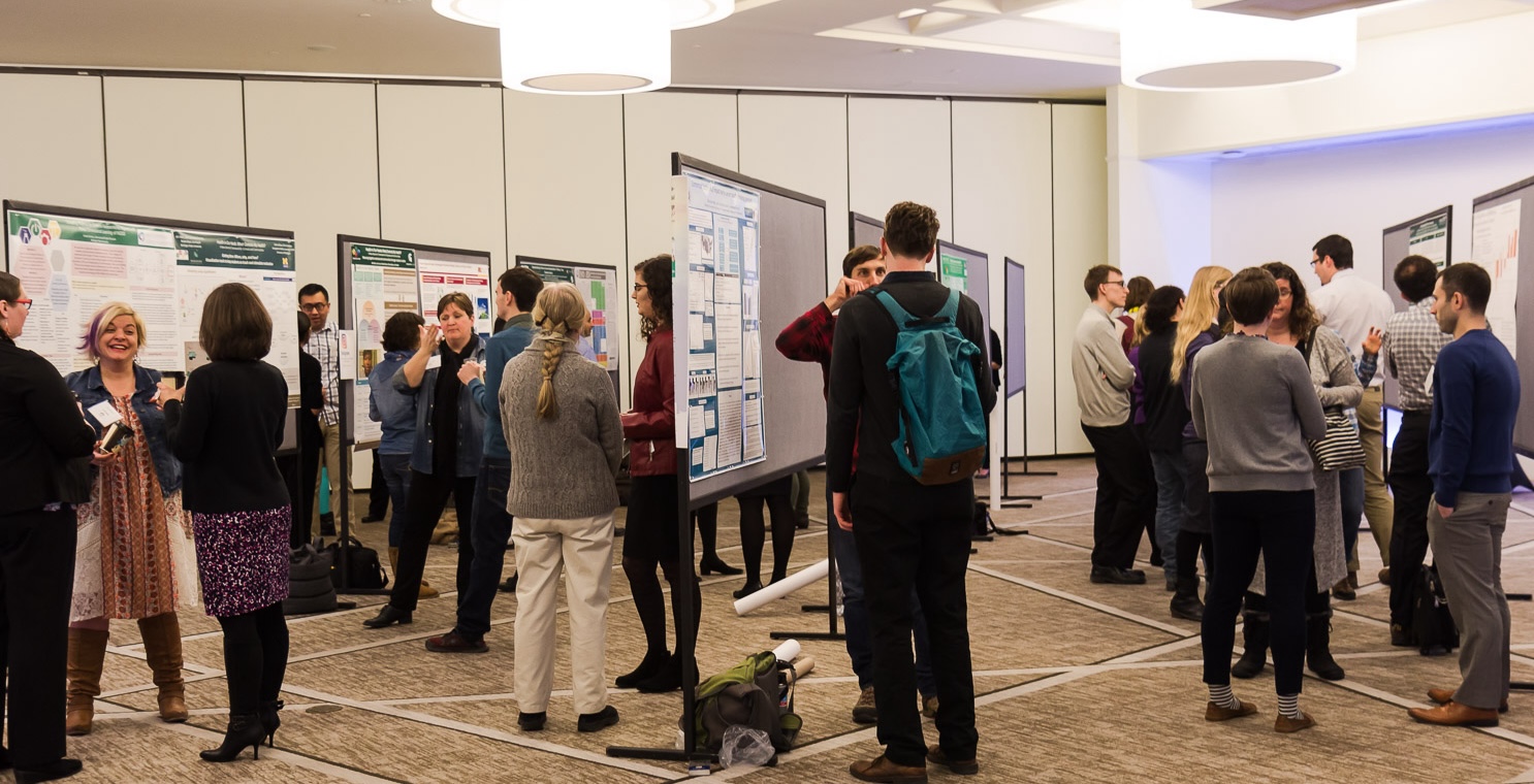 Attendees talking and looking at posters on tackboards