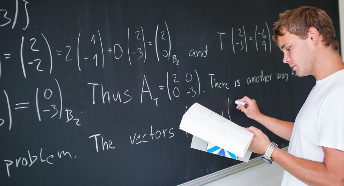 College aged male student doing science problems on blackboard