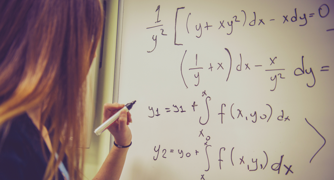 Female student doing mathematics on white board