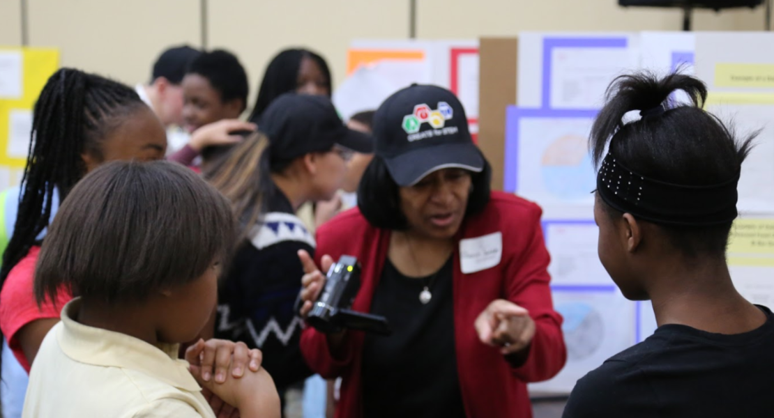 Students presenting projects with community member looking on